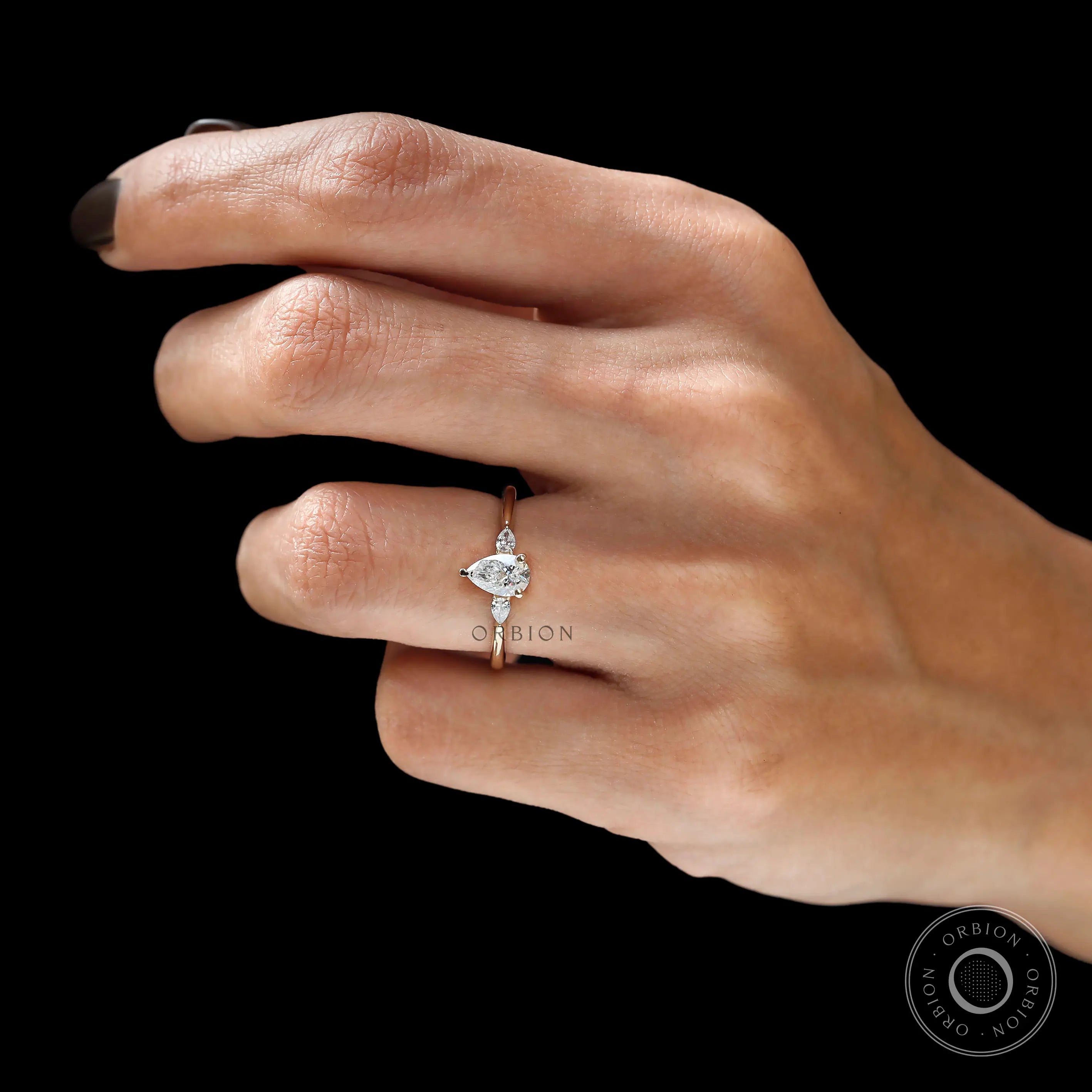 Pear cut trilogy engagement ring yellow gold on finger