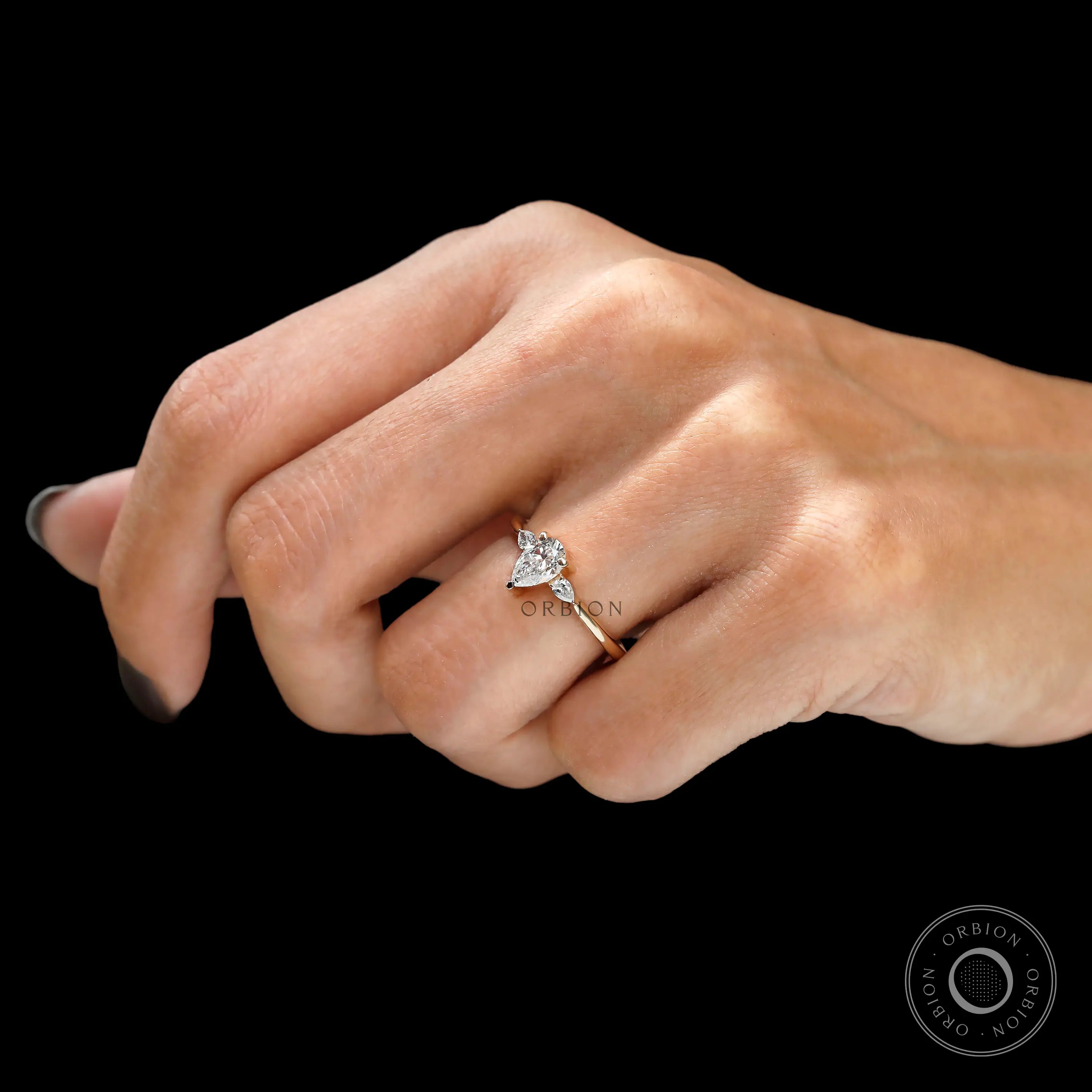 Pear shaped three stone engagement ring on finger