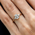 Close up of emerald step cut center stone three stone ring