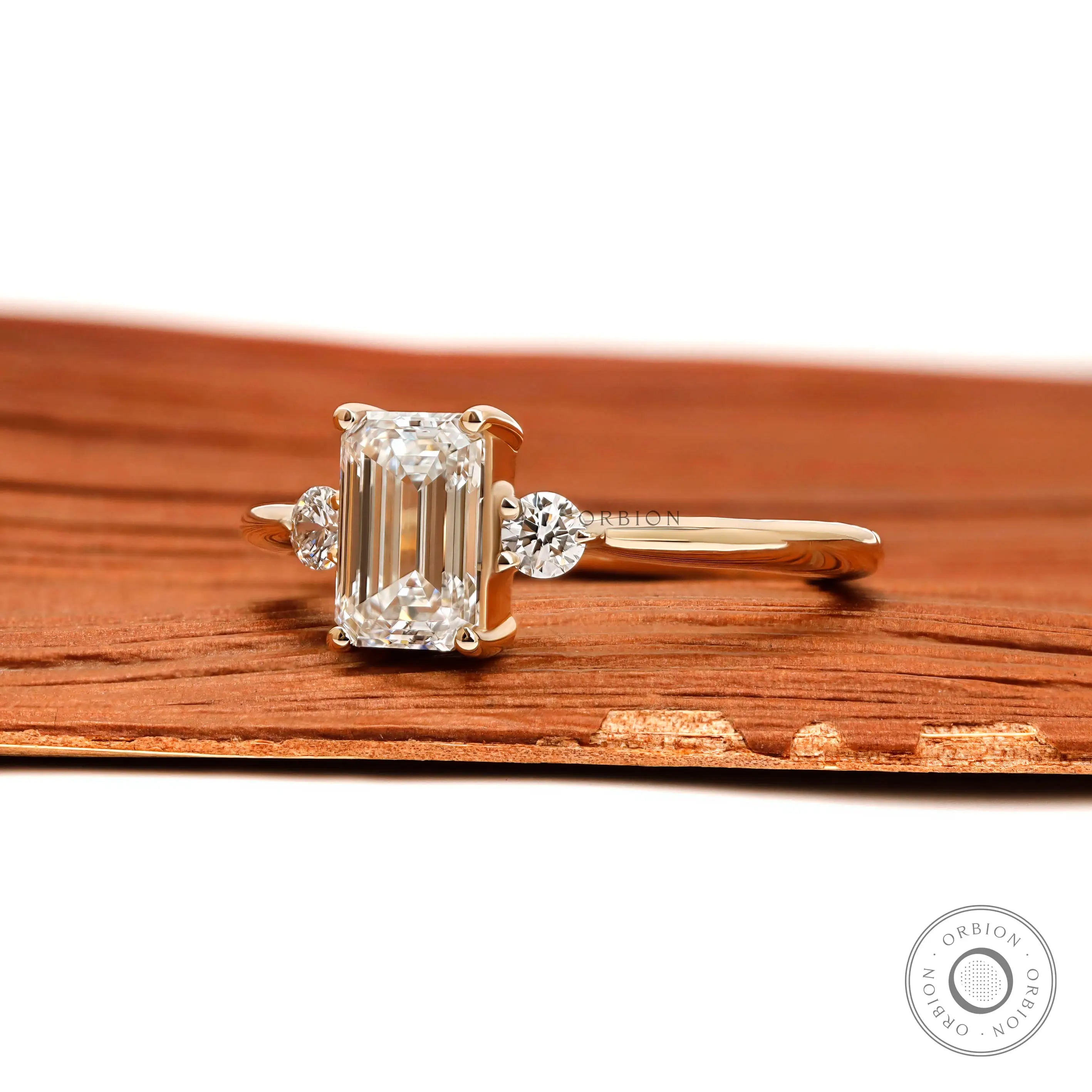 Side profile of emerald cut lab diamond three stone ring yellow gold