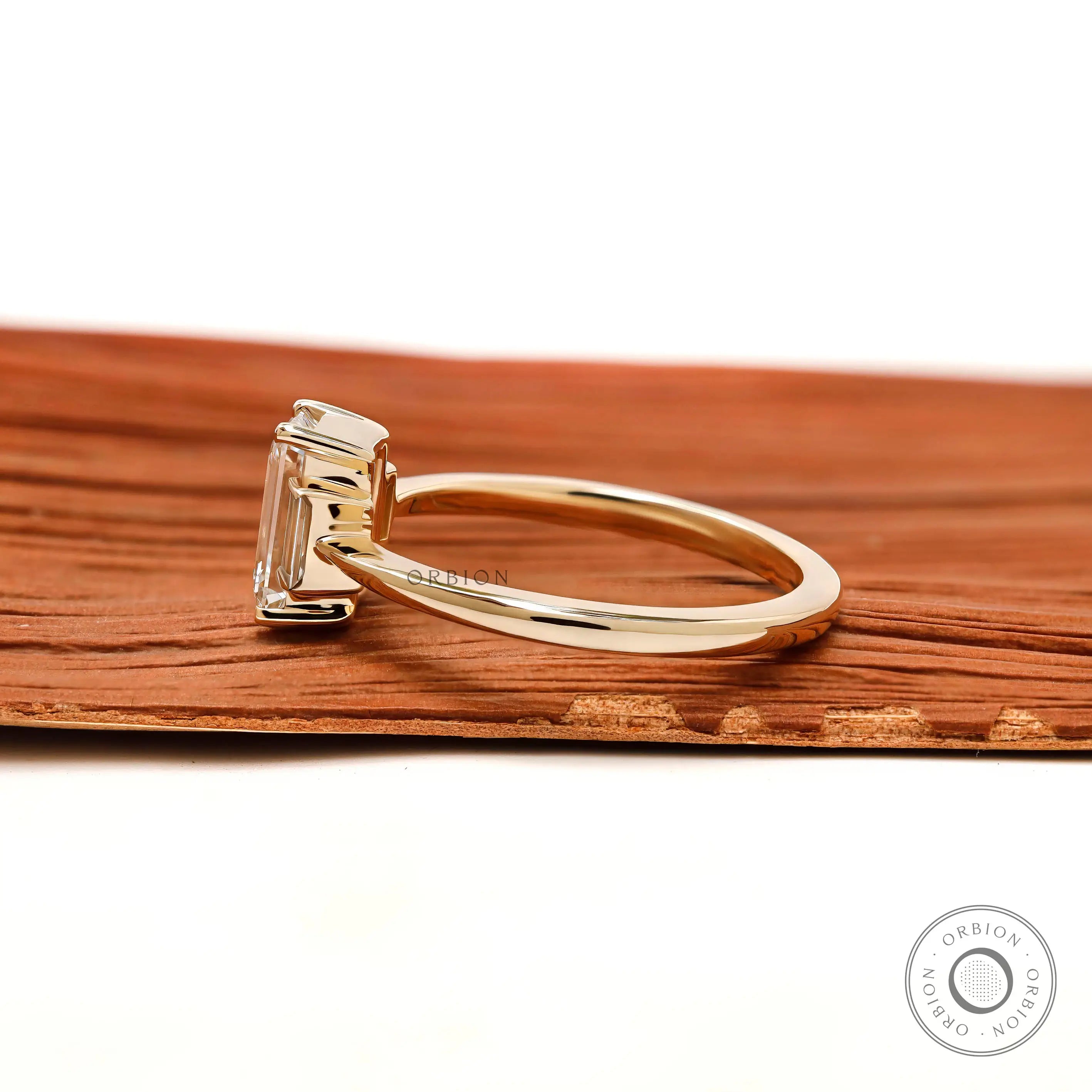 Minimal three stone emerald cut engagement ring yellow gold