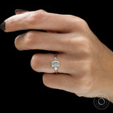 Emerald cut engagement ring with pear side stones on finger