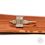 Side view of emerald and pear three stone engagement ring