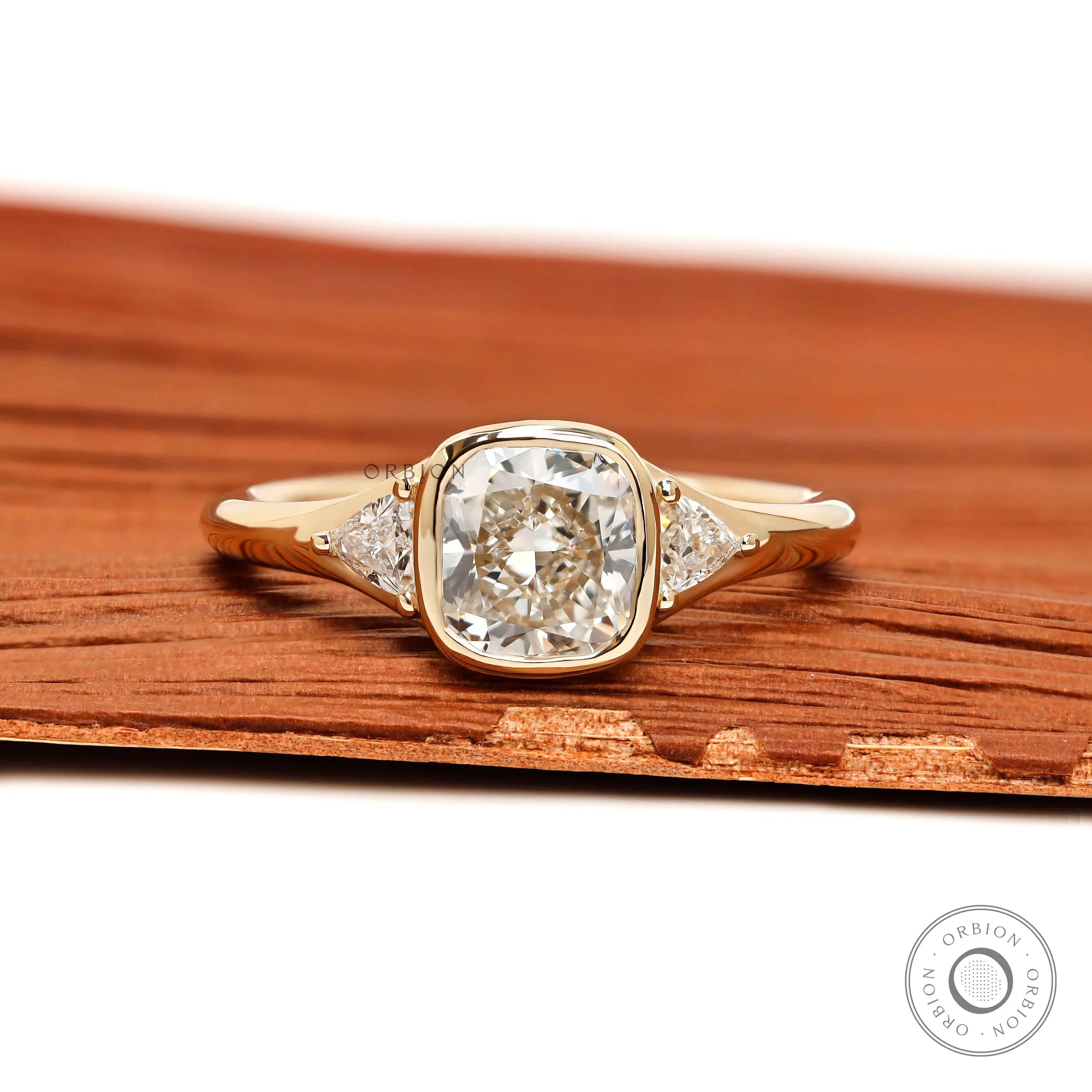 Floating three stone cushion bezel engagement ring with trillion side stones in yellow gold