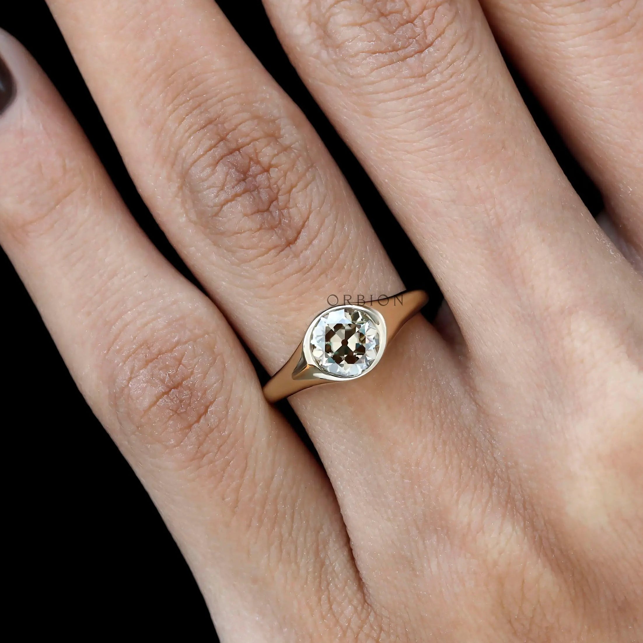 Close up of bezel setting champagne moissanite signet ring