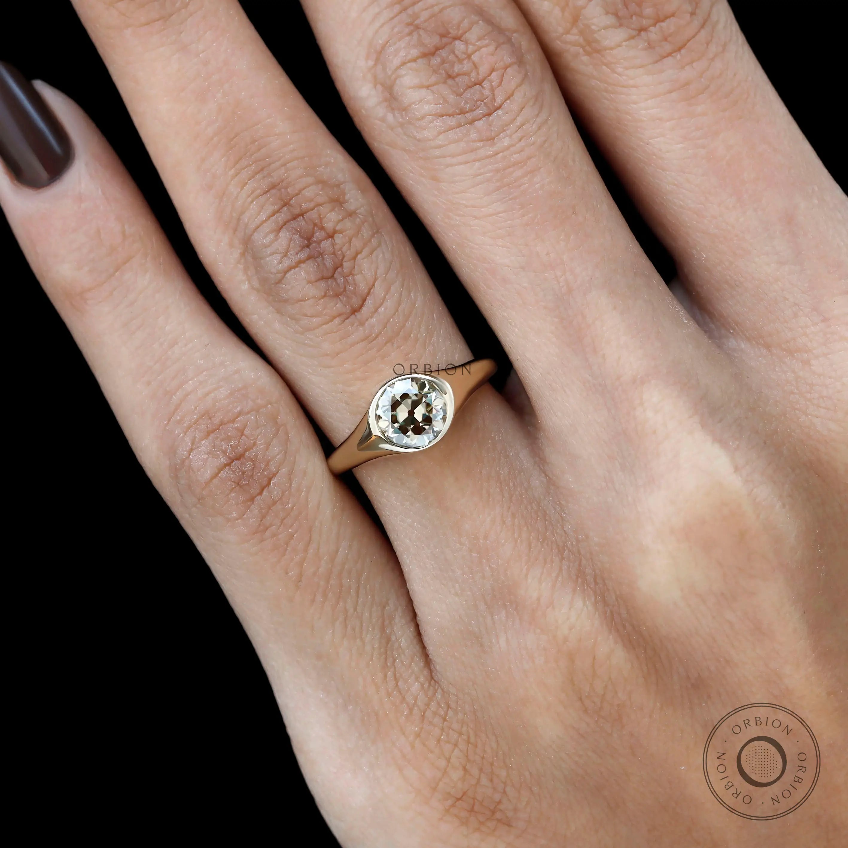 Close up of bezel setting champagne moissanite signet ring