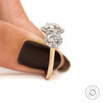 Hand shot of three stone halo engagement ring in yellow and white gold