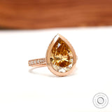 Pear light champagne moissanite pave bezel halo engagement ring in 14k rose gold