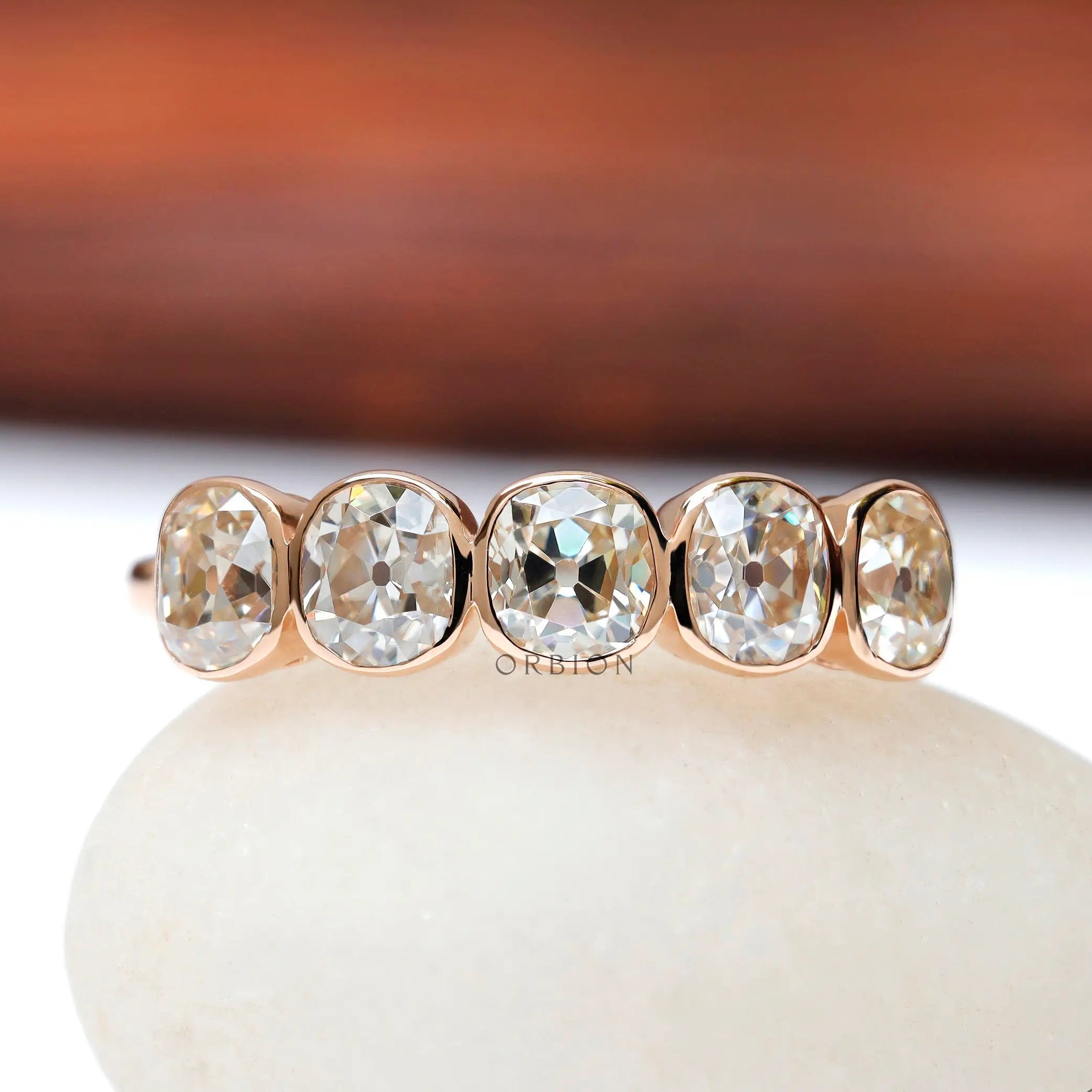 Five elongated cushion moissanites bezel set in rose gold band