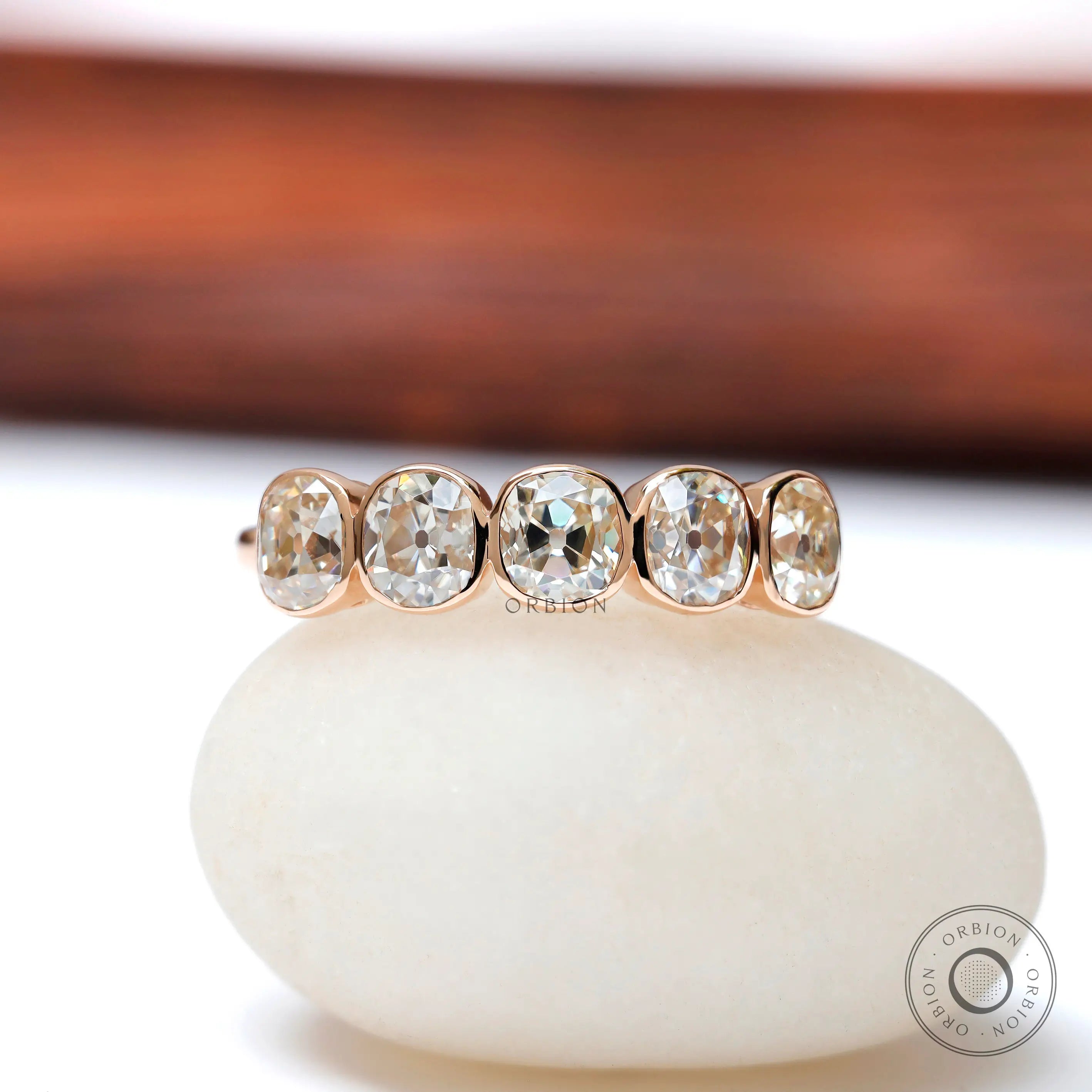 Five elongated cushion moissanites bezel set in rose gold band