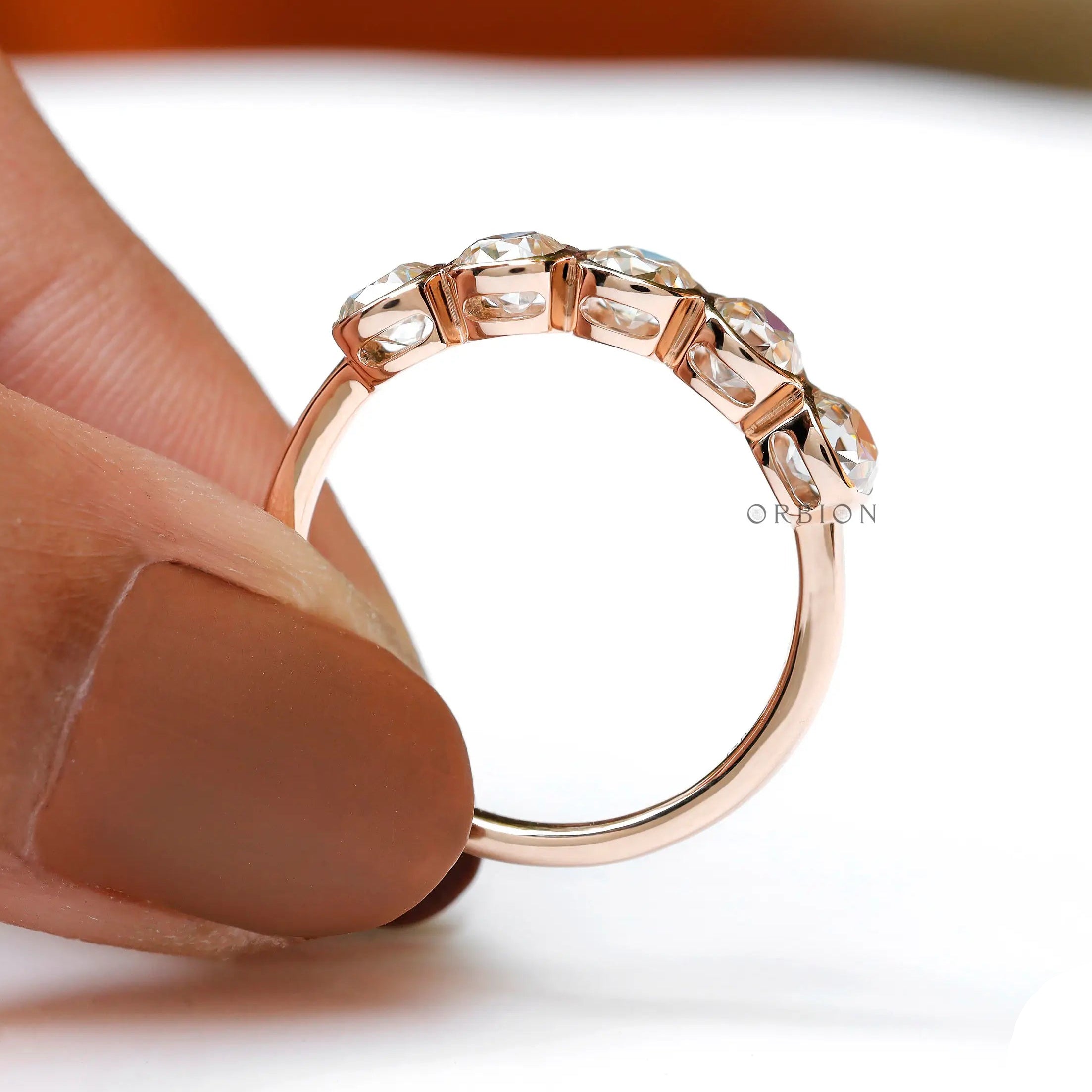 Handheld view of rose gold band with open bezels