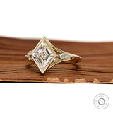 Unique three stone moissanite engagement ring with lozenge cut and yellow gold split shank