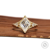 Bezel set lozenge cut moissanite three stone engagement ring with kite accents