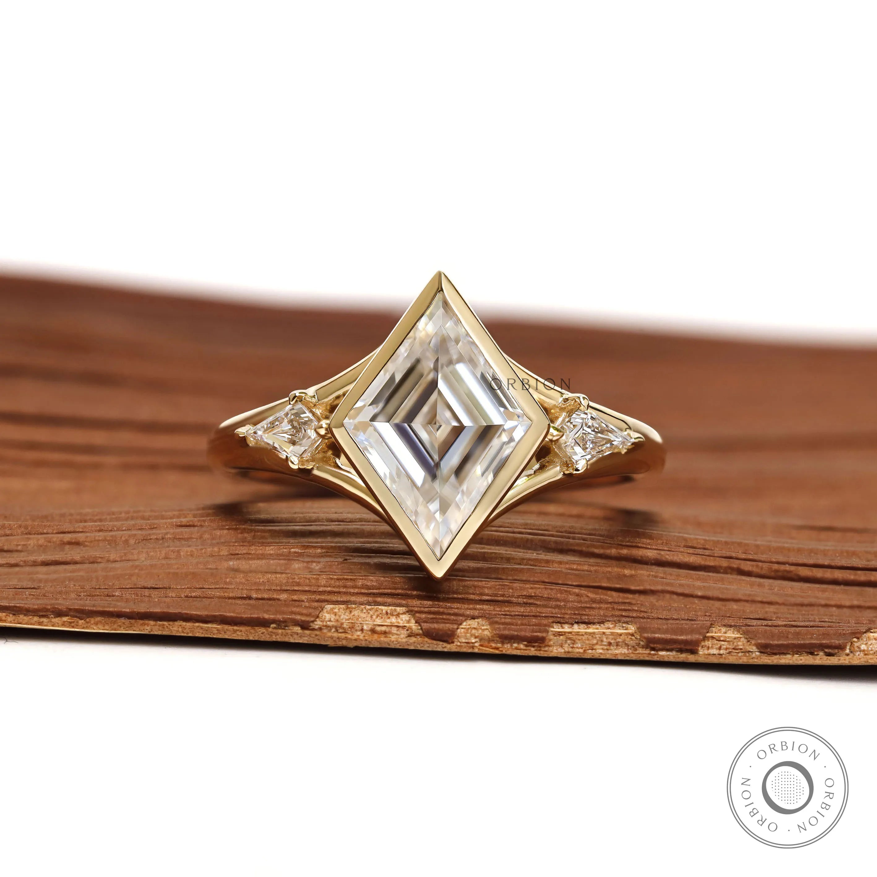 Bezel set lozenge cut moissanite three stone engagement ring with kite accents