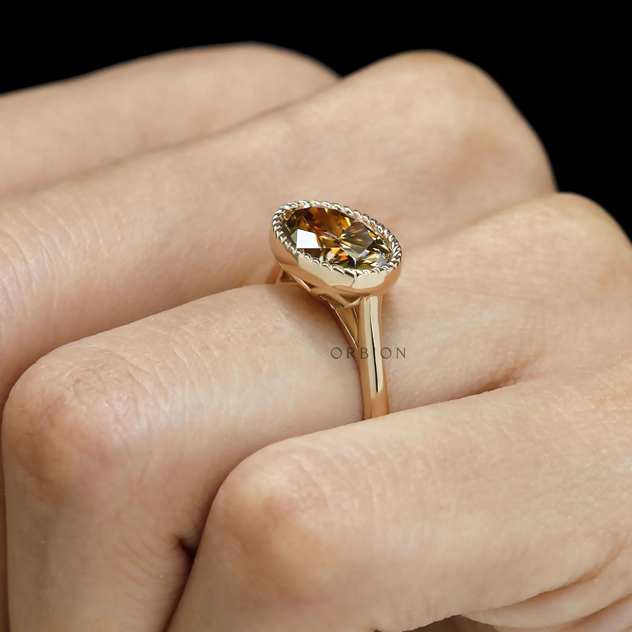 Oval East West moissanite ring in dark champagne, tulip set with 18k yellow gold rope bezel