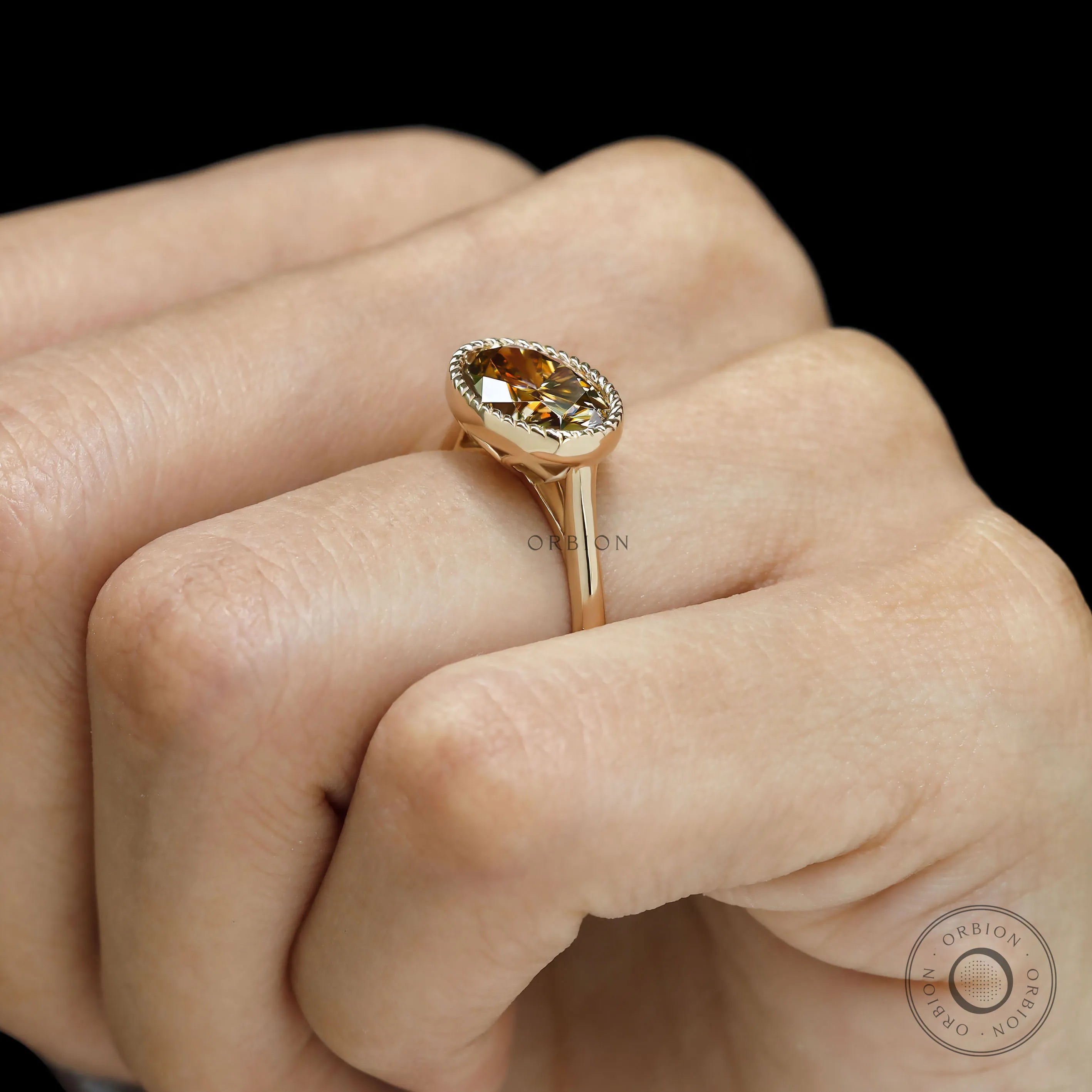 Oval East West moissanite ring in dark champagne, tulip set with 18k yellow gold rope bezel