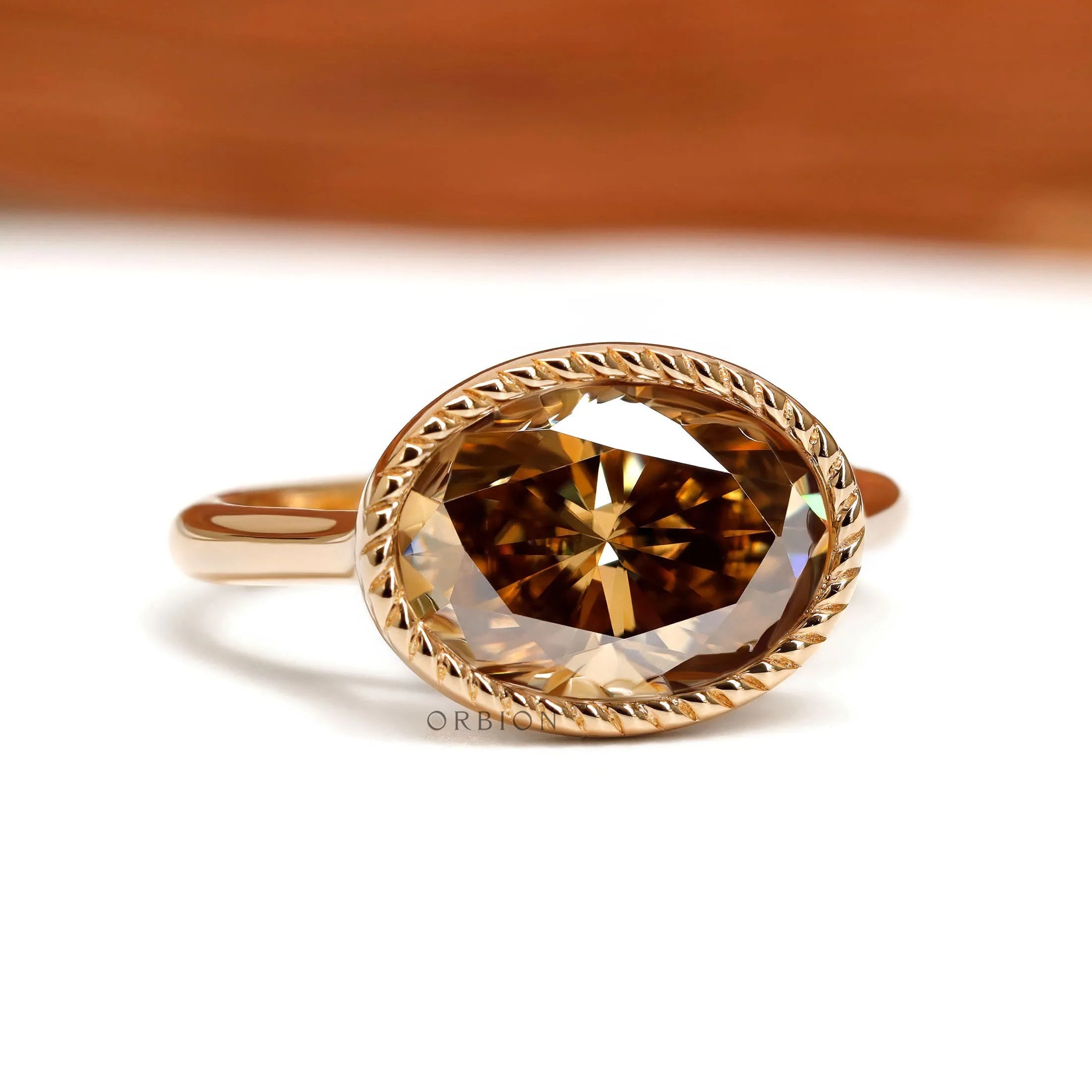 Dark champagne oval moissanite ring in East West orientation with rope bezel and tulip setting