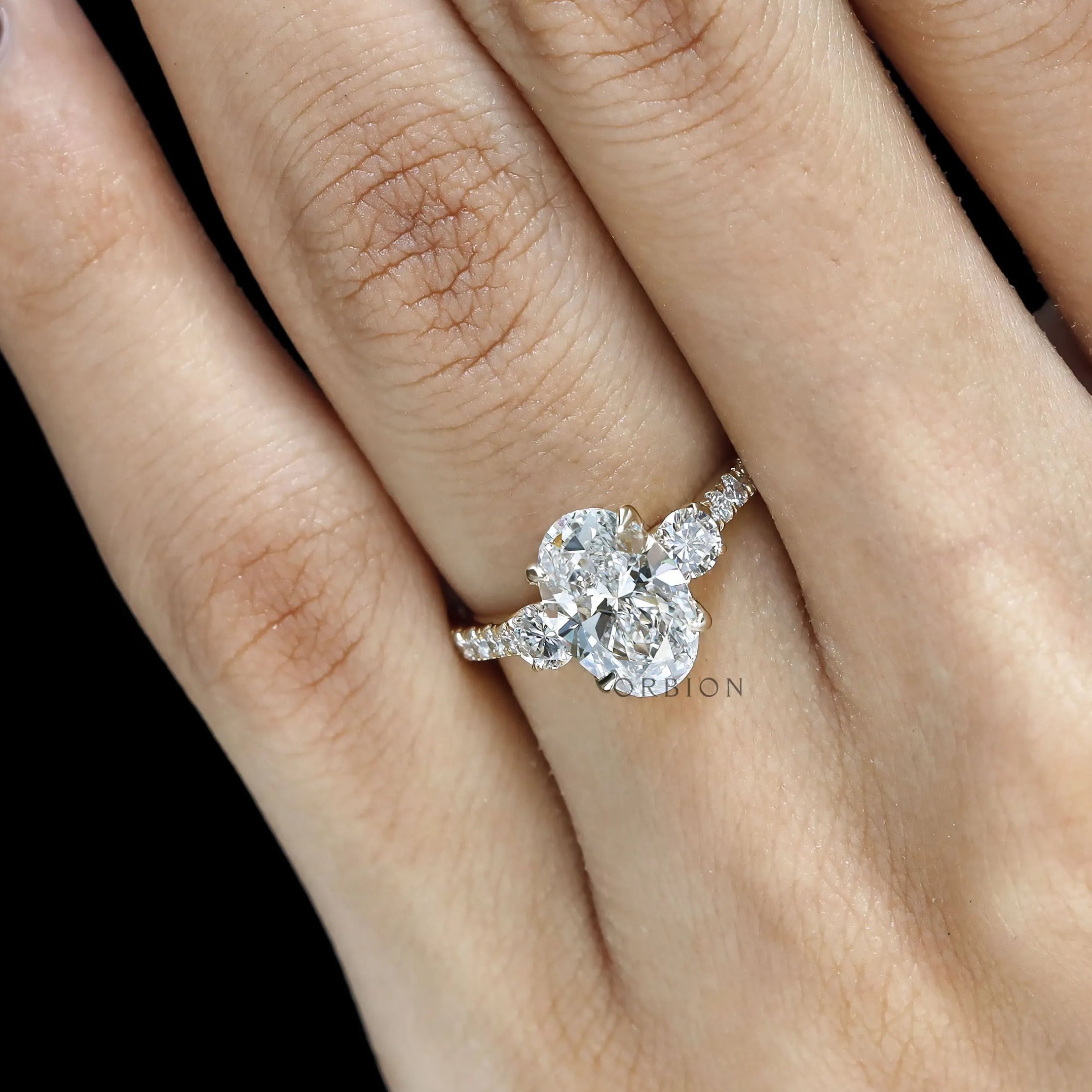 Three stone engagement ring featuring oval moissanite in 14k yellow gold 