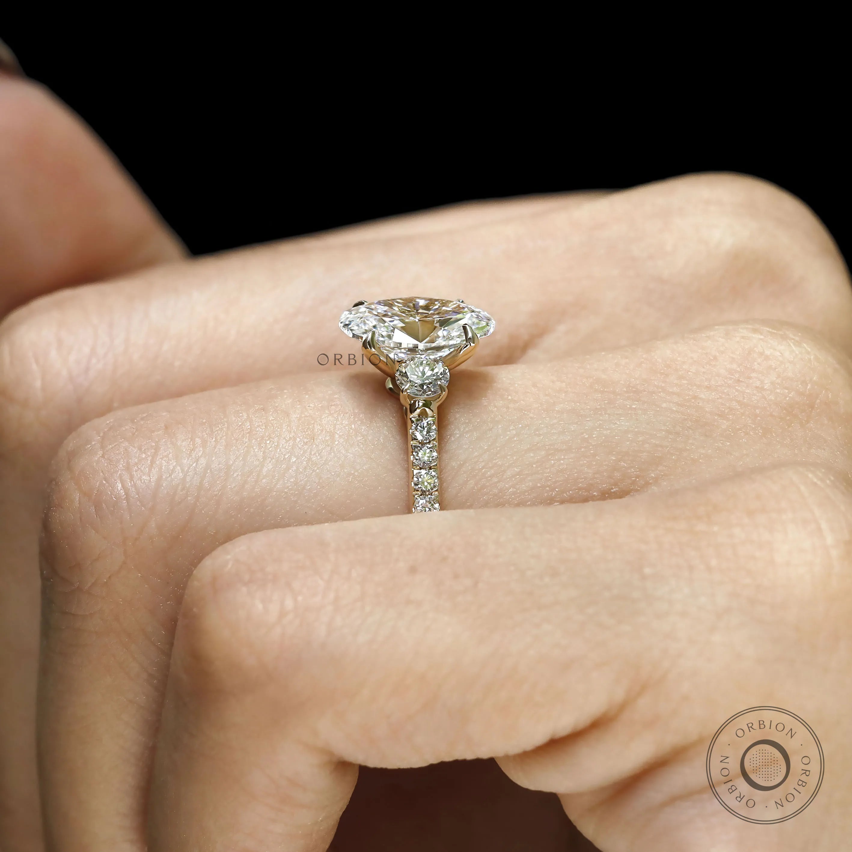 Oval lab grown diamond engagement ring with three stones, yellow gold cathedral band, pave shank