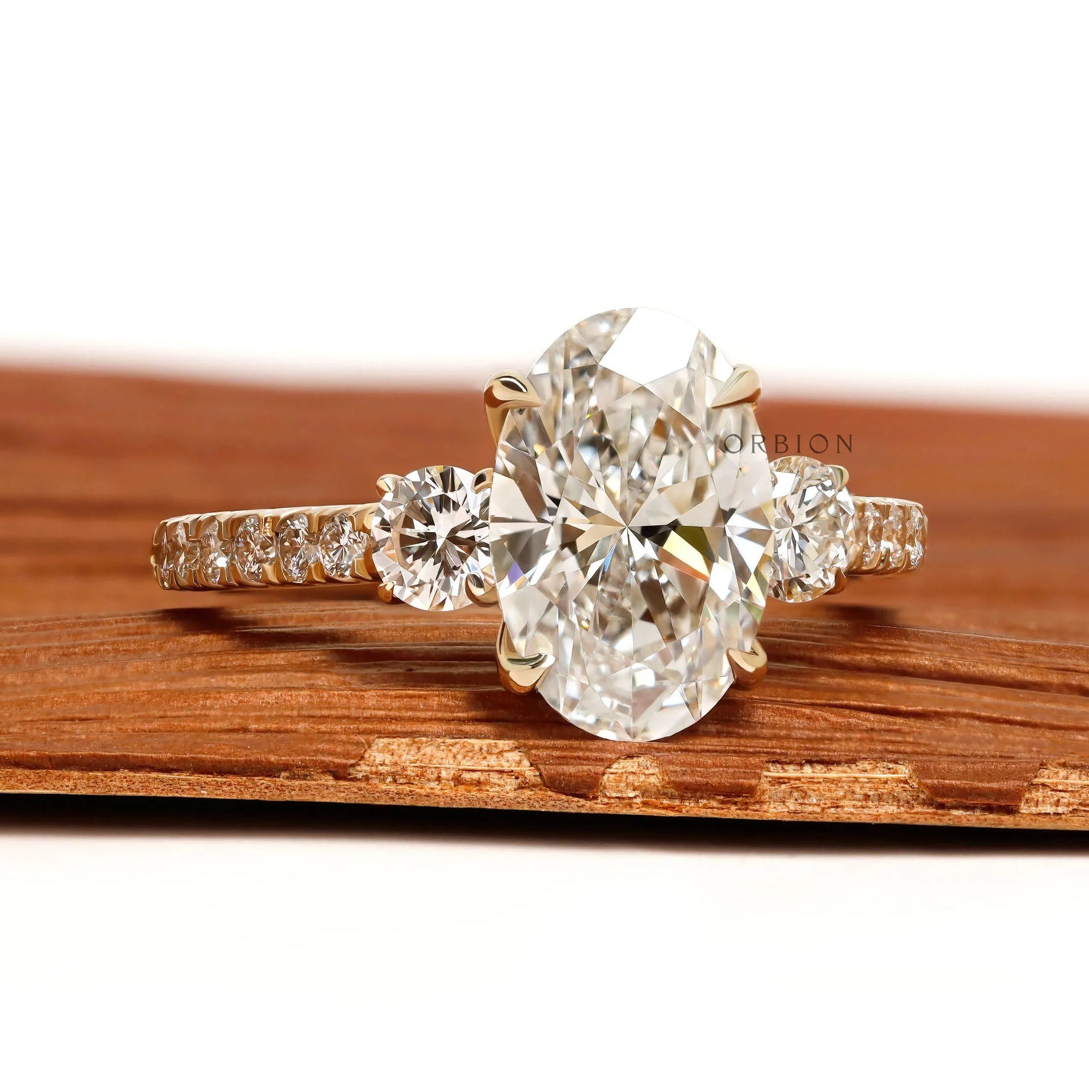 14k yellow gold three stone engagement ring with oval lab grown diamond and pave shank