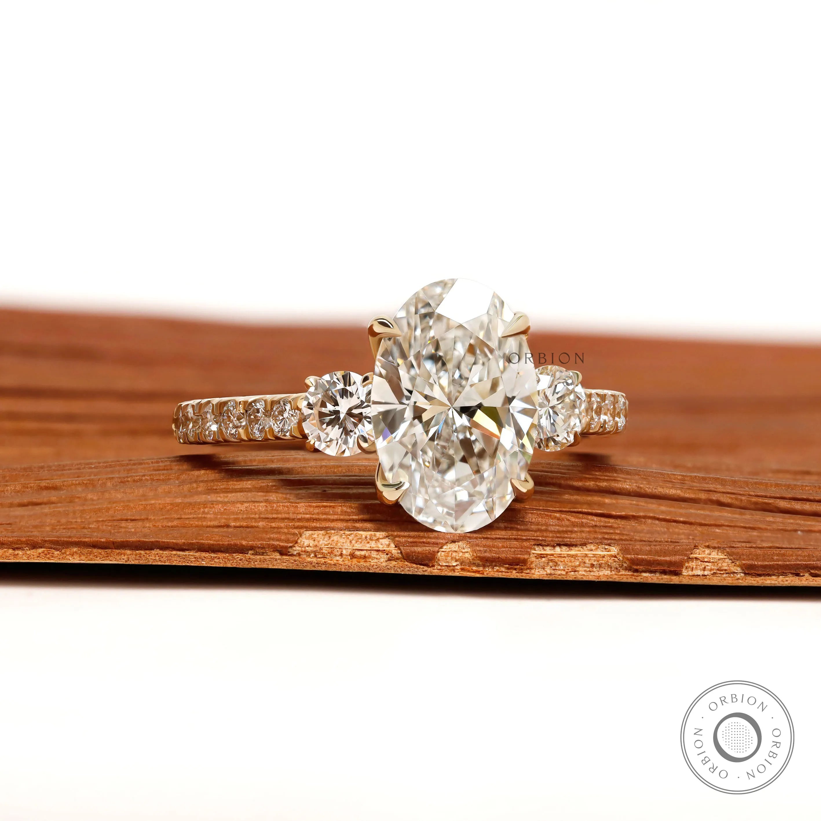 14k yellow gold three stone engagement ring with oval lab grown diamond and pave shank