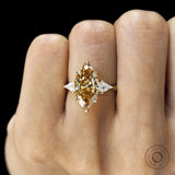 Three stone marquise champagne moissanite ring with tulip set and kite side stones, yellow gold cathedral