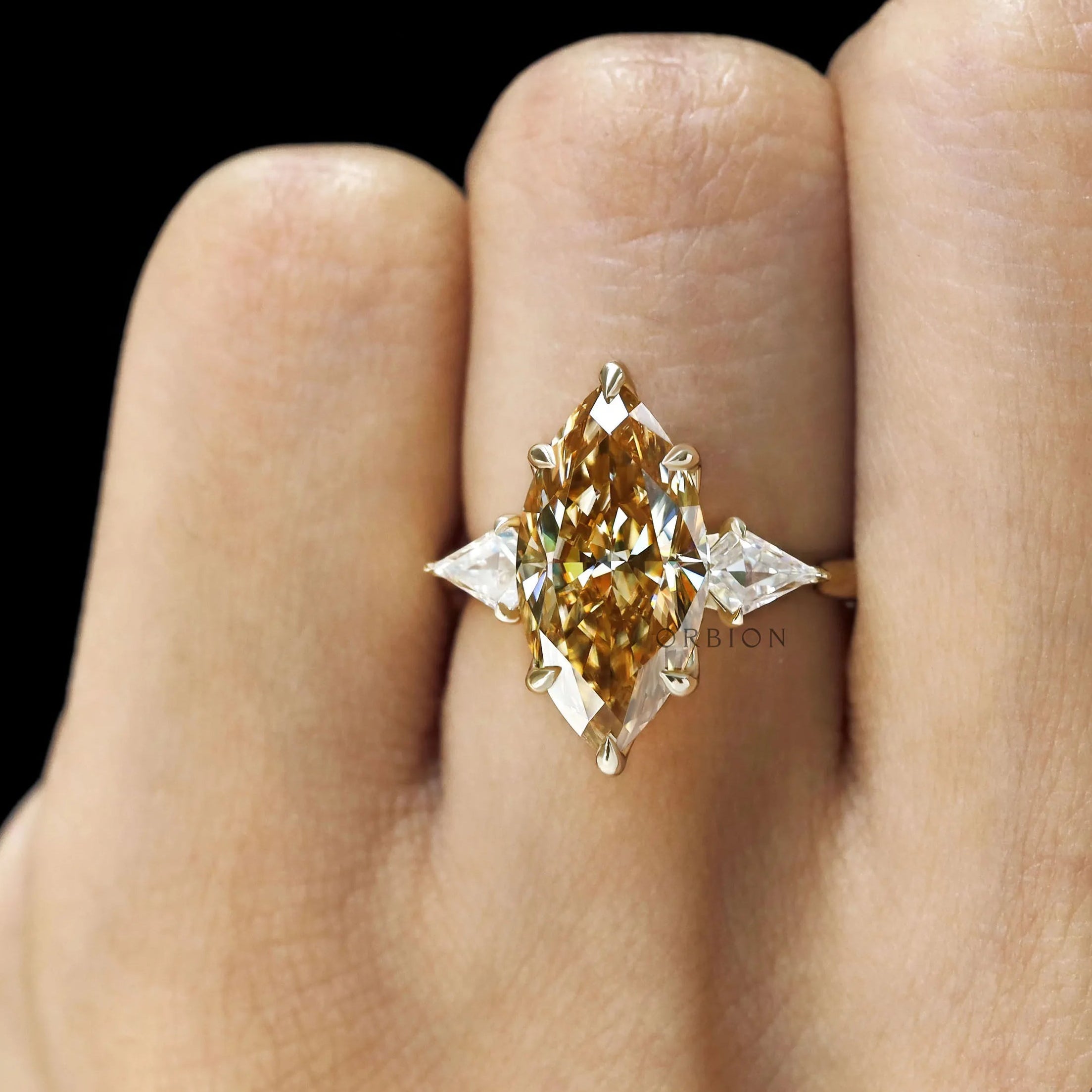 Three stone marquise champagne moissanite ring with tulip set and kite side stones, yellow gold cathedral