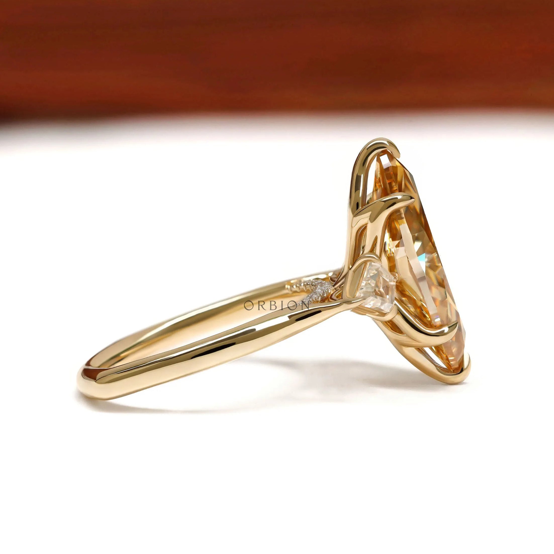 Marquise champagne moissanite three stone engagement ring with tulip set and kite accents in yellow gold