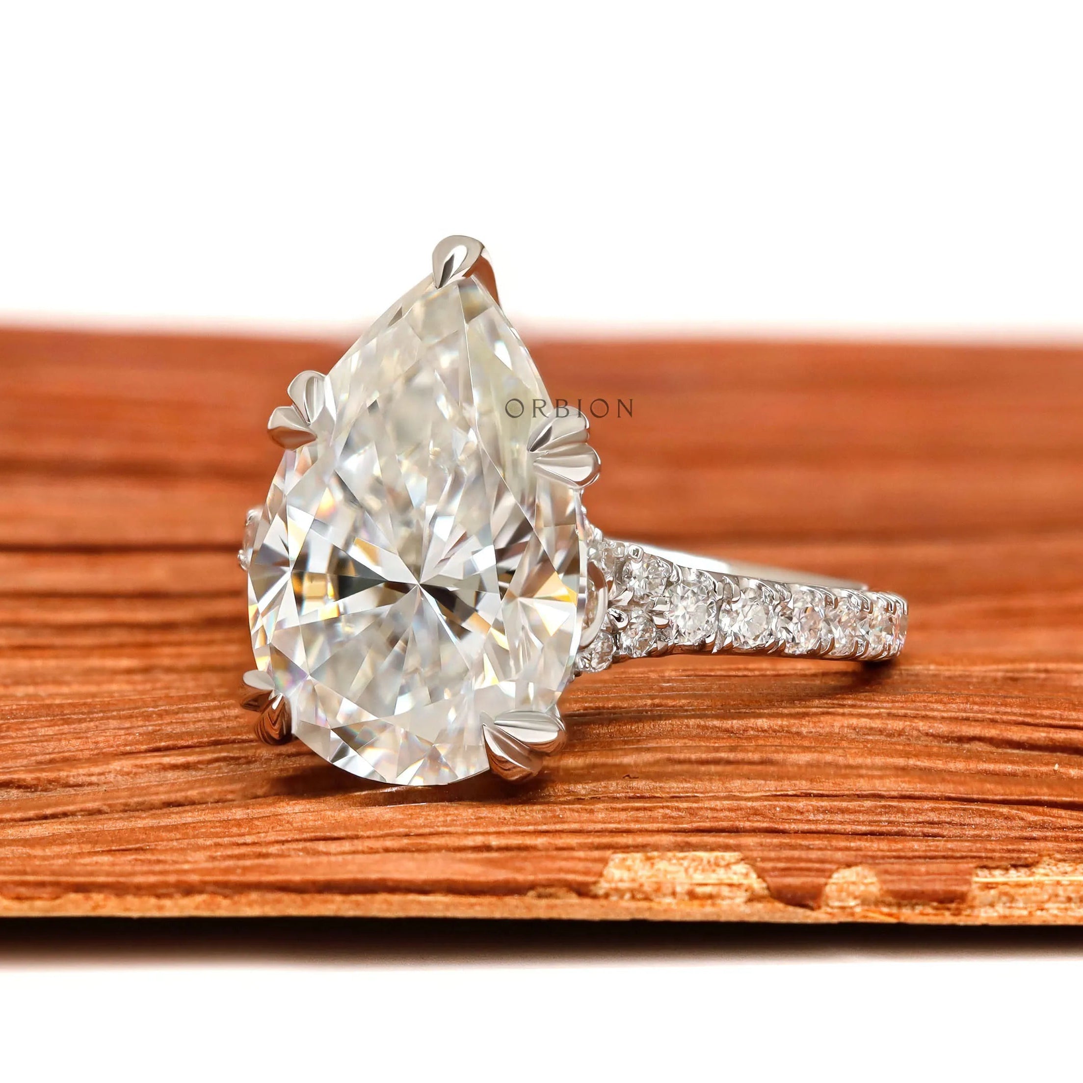 Pear shaped moissanite engagement ring with cathedral setting and pave band