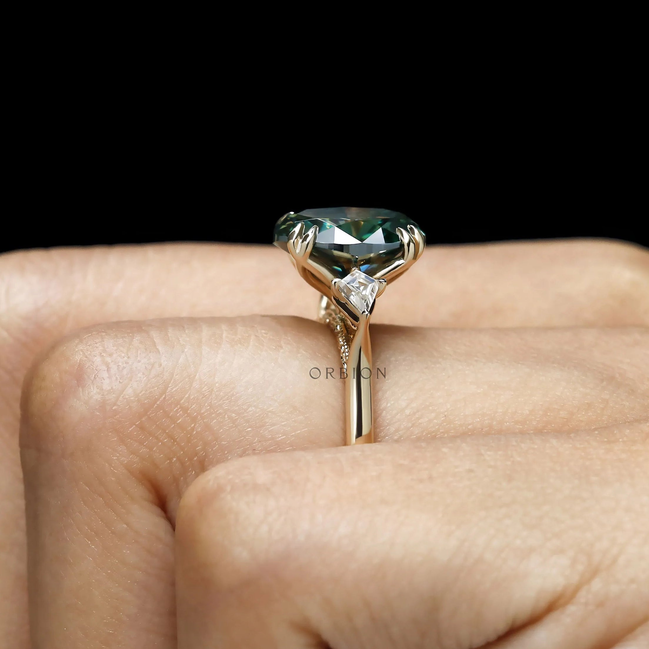 Yellow gold 3 stone color gemstone ring with oval blue green moissanite and kite accents.
