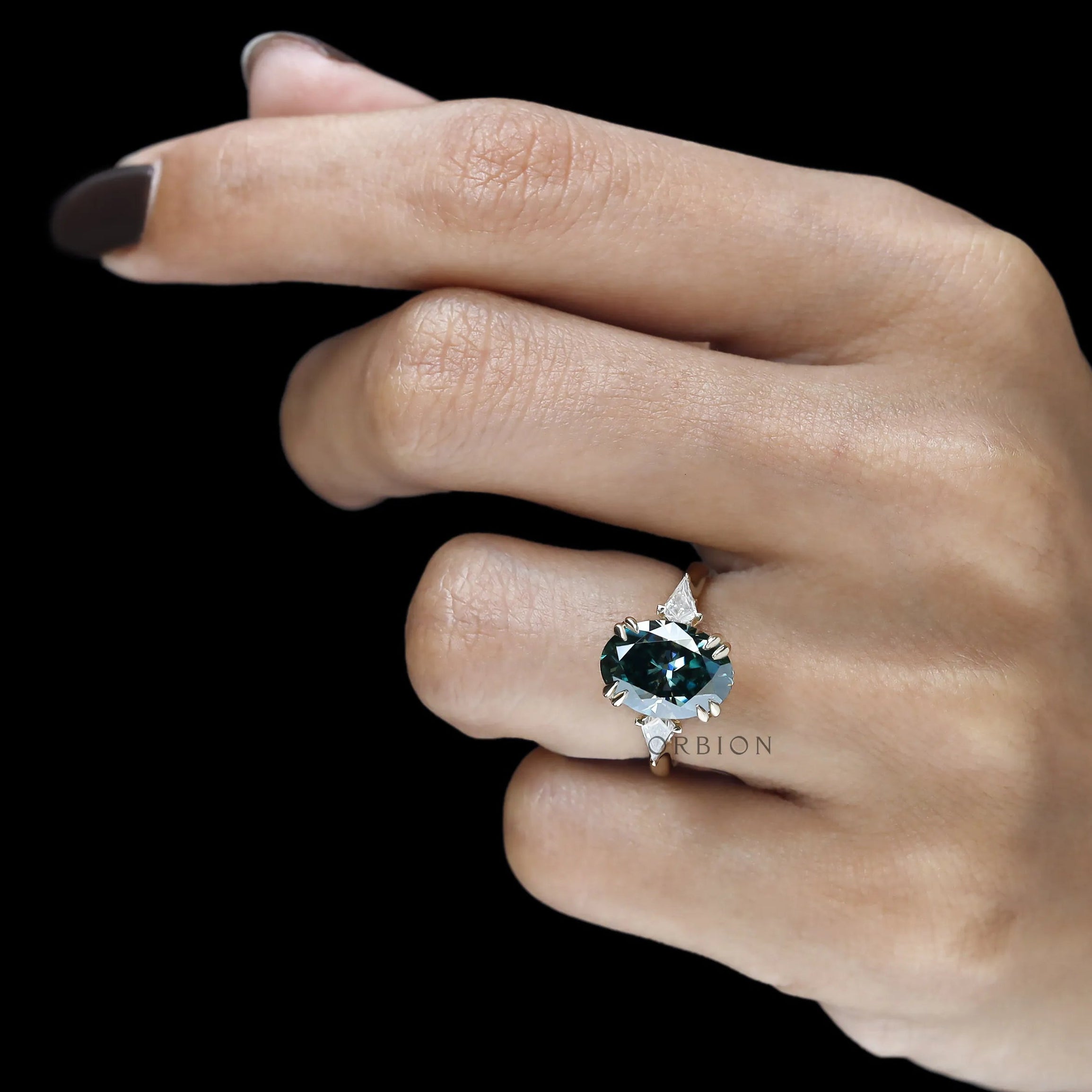 Oval blue green moissanite three stone ring with floral bridge and kite accents in yellow gold