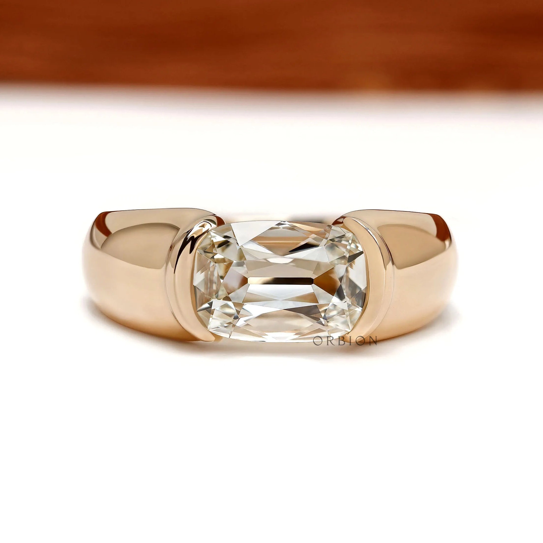 Men’s lab grown diamond engagement ring with east west elongated cushion stone and chunky 14k yellow gold half bezel setting