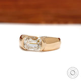 Mens moissanite wedding ring featuring an elongated cushion cut stone in an east west 14k yellow gold setting