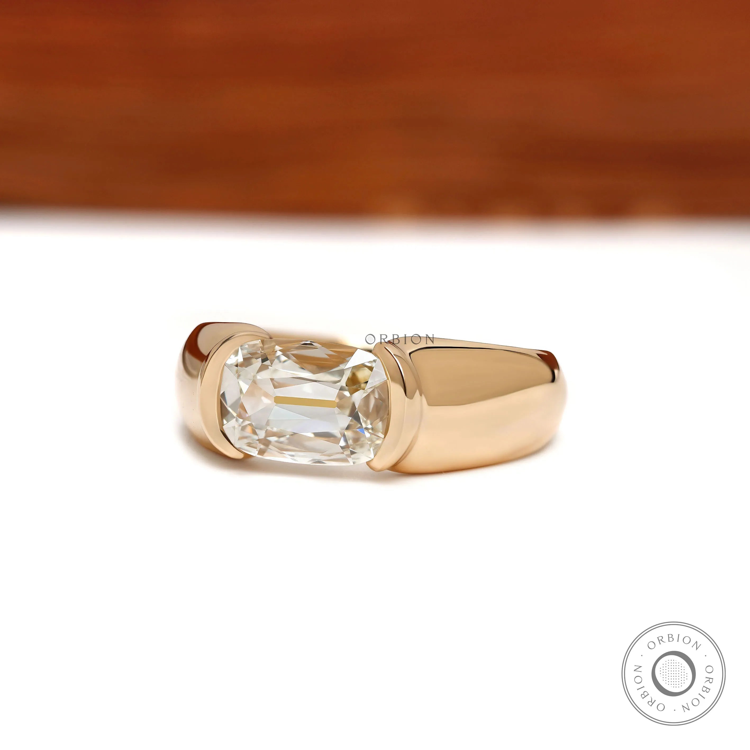 Mens moissanite wedding ring featuring an elongated cushion cut stone in an east west 14k yellow gold setting