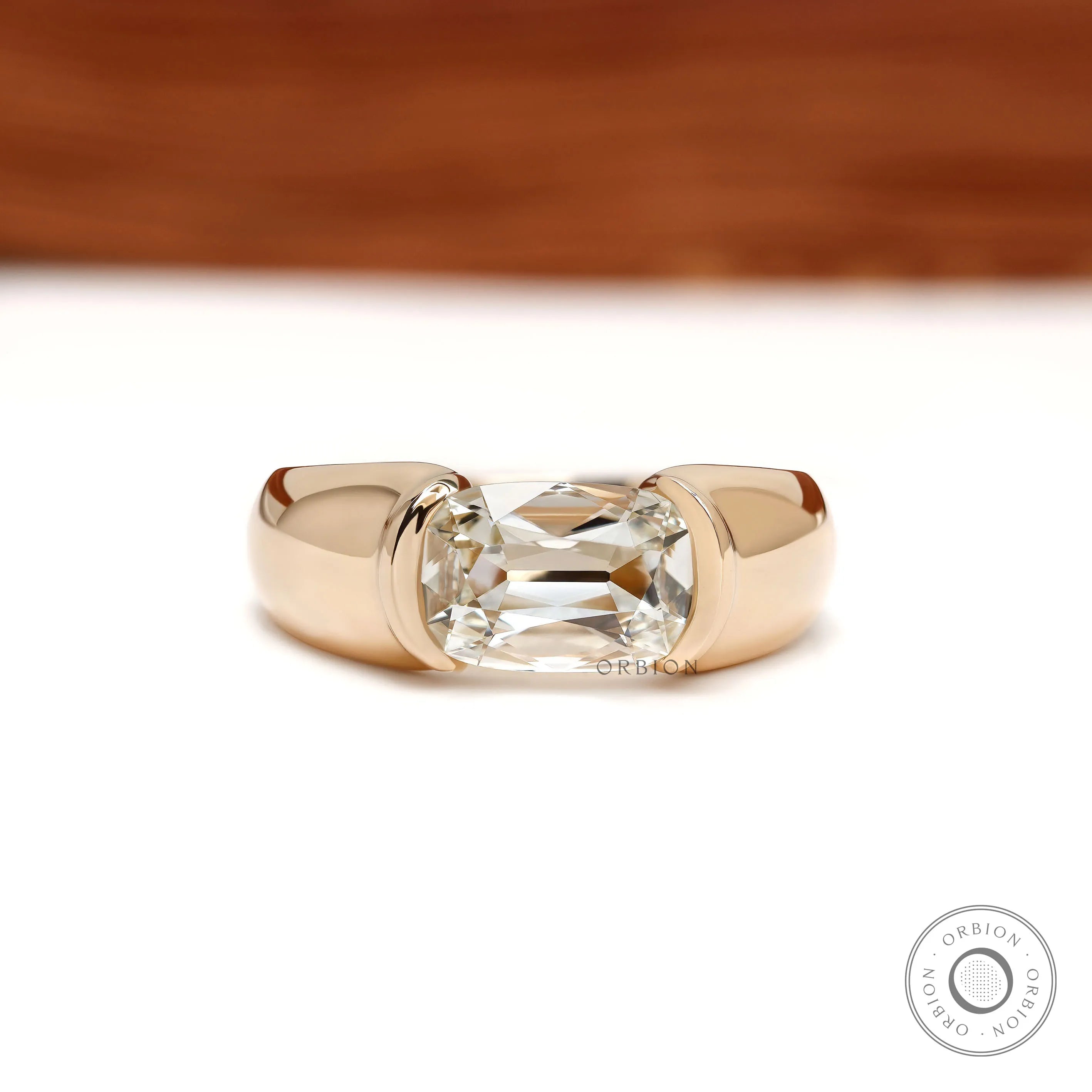 Men’s lab grown diamond engagement ring with east west elongated cushion stone and chunky 14k yellow gold half bezel setting
