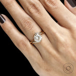 Fine jewelry bypass ring with round moissanite gemstone, compass setting, and curved crossover yellow gold band