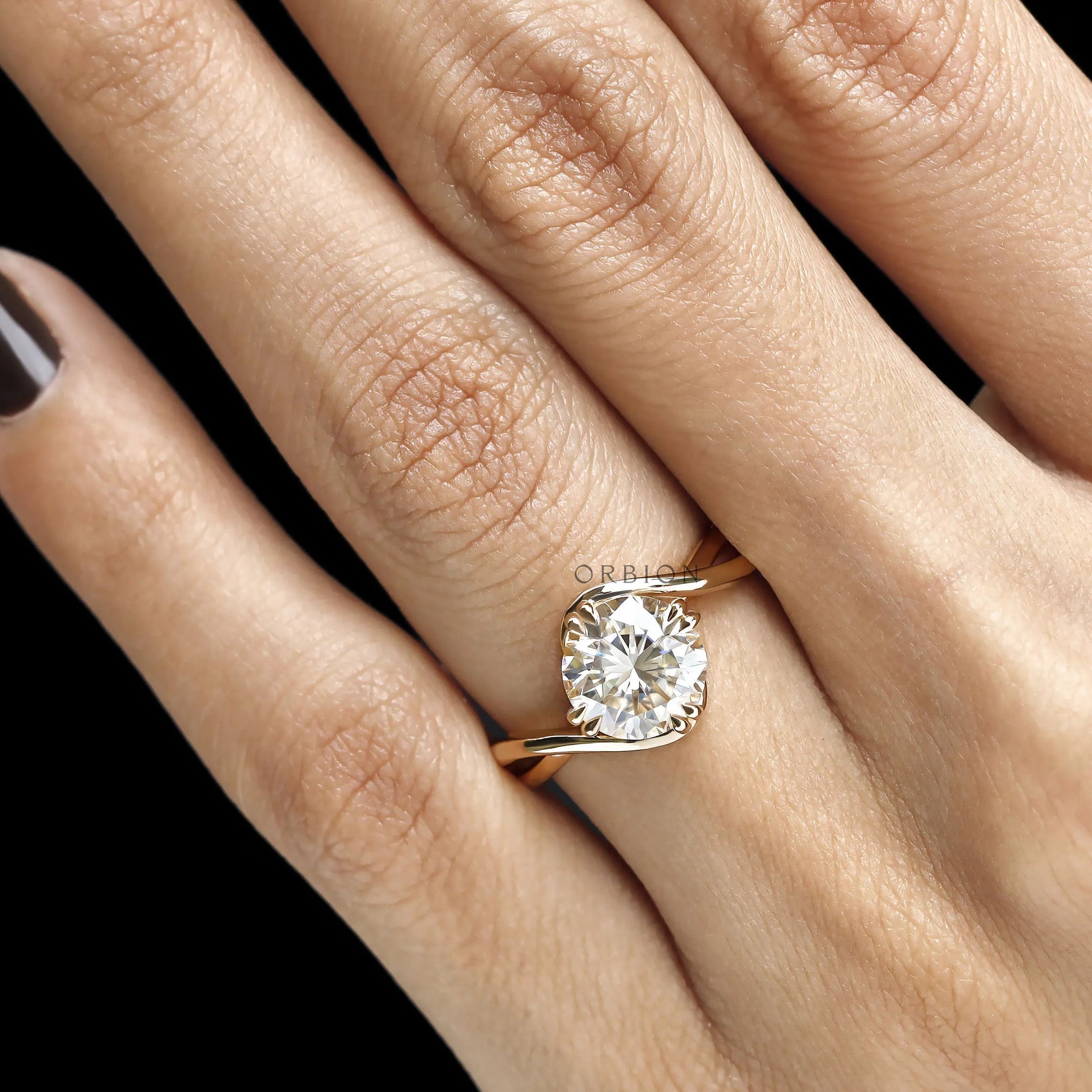 Fine jewelry bypass ring with round moissanite gemstone, compass setting, and curved crossover yellow gold band