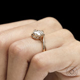Lab diamond or moissanite crossover engagement ring featuring round cut stone and artistic swirl solitaire design
