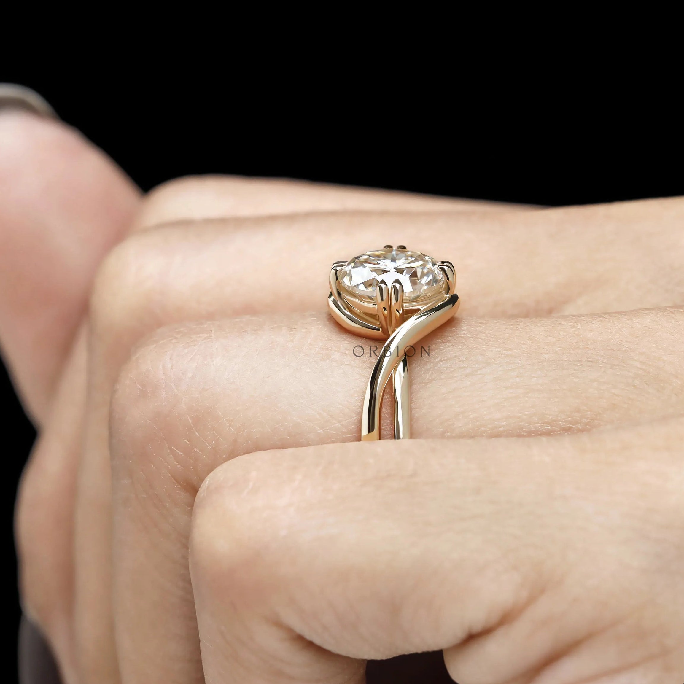 14k yellow gold alternative engagement ring with round moissanite, twisted bypass band and claw prong setting