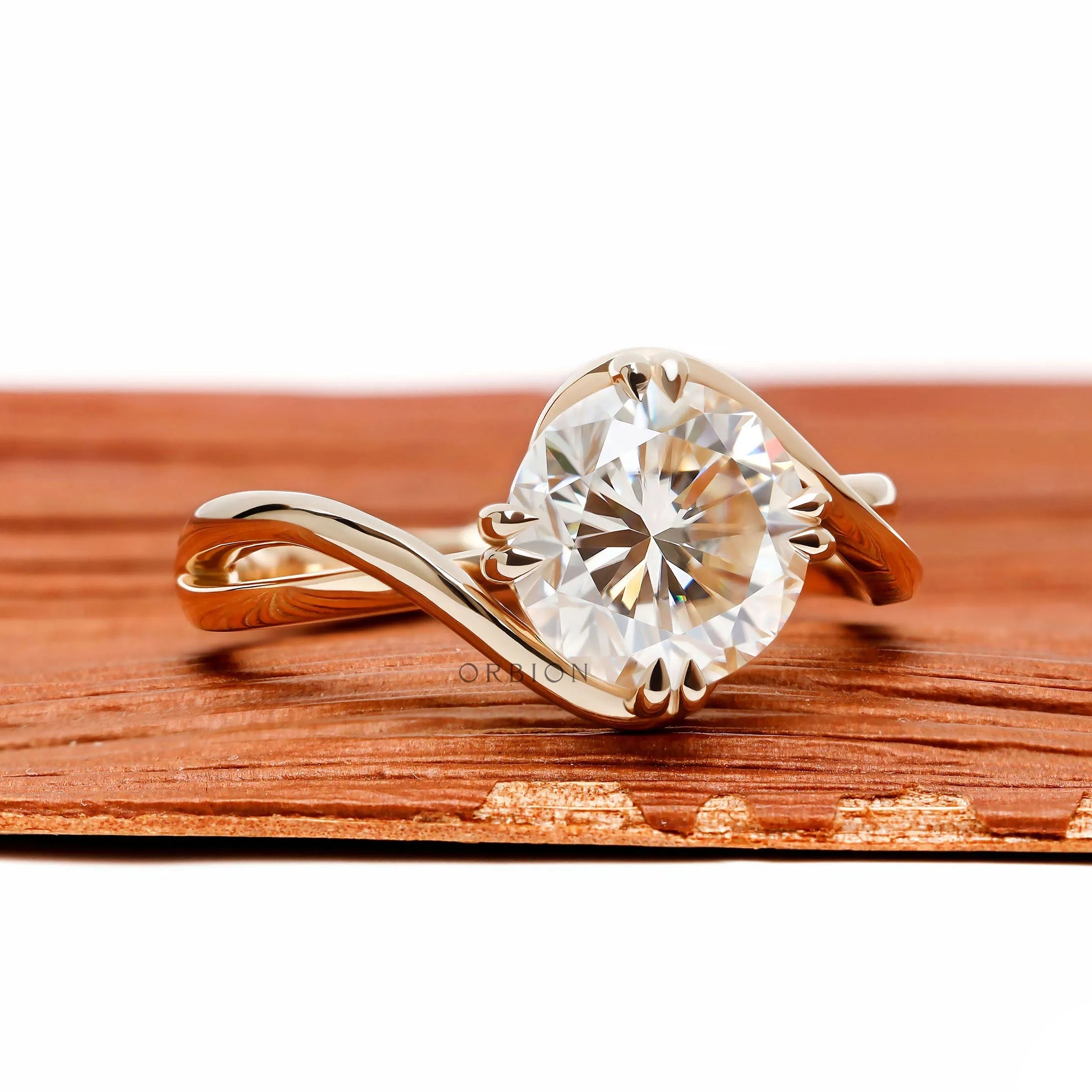 14k yellow gold swirl solitaire ring featuring round cut moissanite with unique crossover bypass design