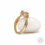 Modern crossover moissanite or lab diamond engagement ring in yellow gold with swirl solitaire setting 