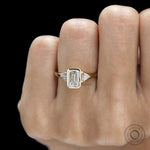 Contemporary emerald cut bezel engagement ring with three gemstone trilogy setting and minimalist gold band