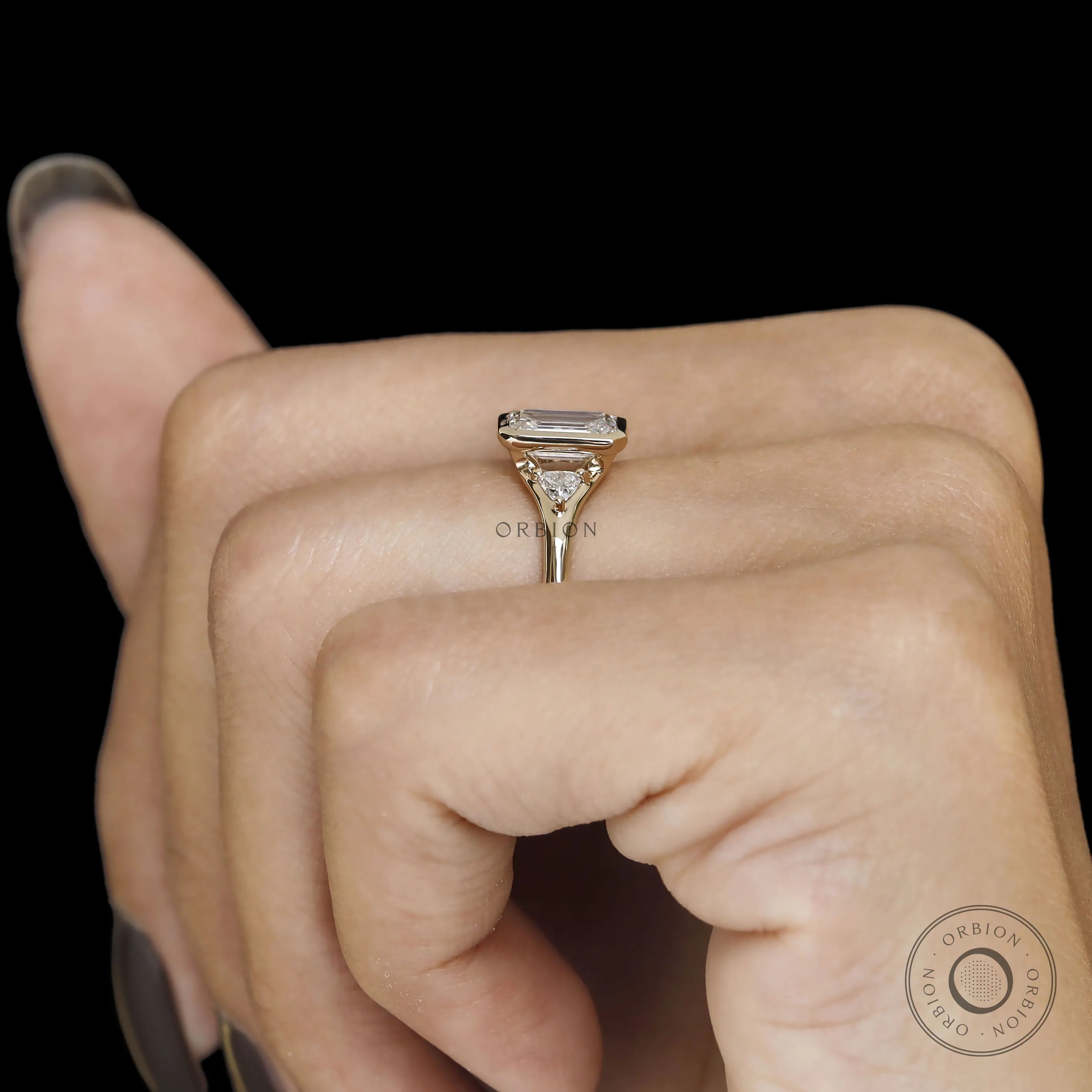 Minimalist wedding ring with emerald cut trilogy stones, bezel setting and 14k yellow gold craftsmanship