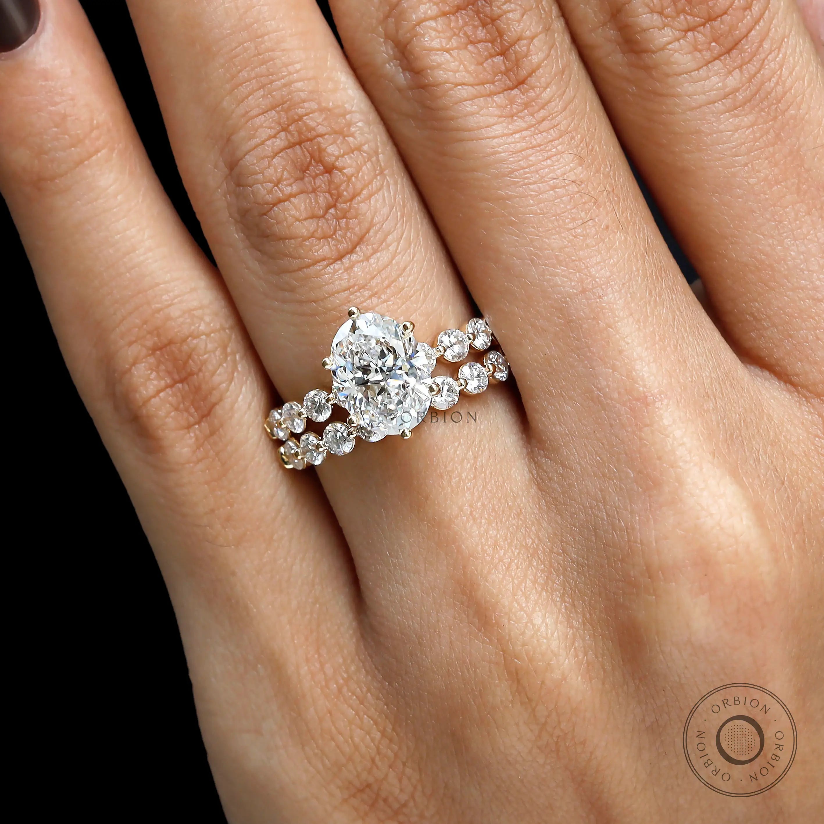 Slight angled on-hand view of oval lab diamond ring with matching shared prong band