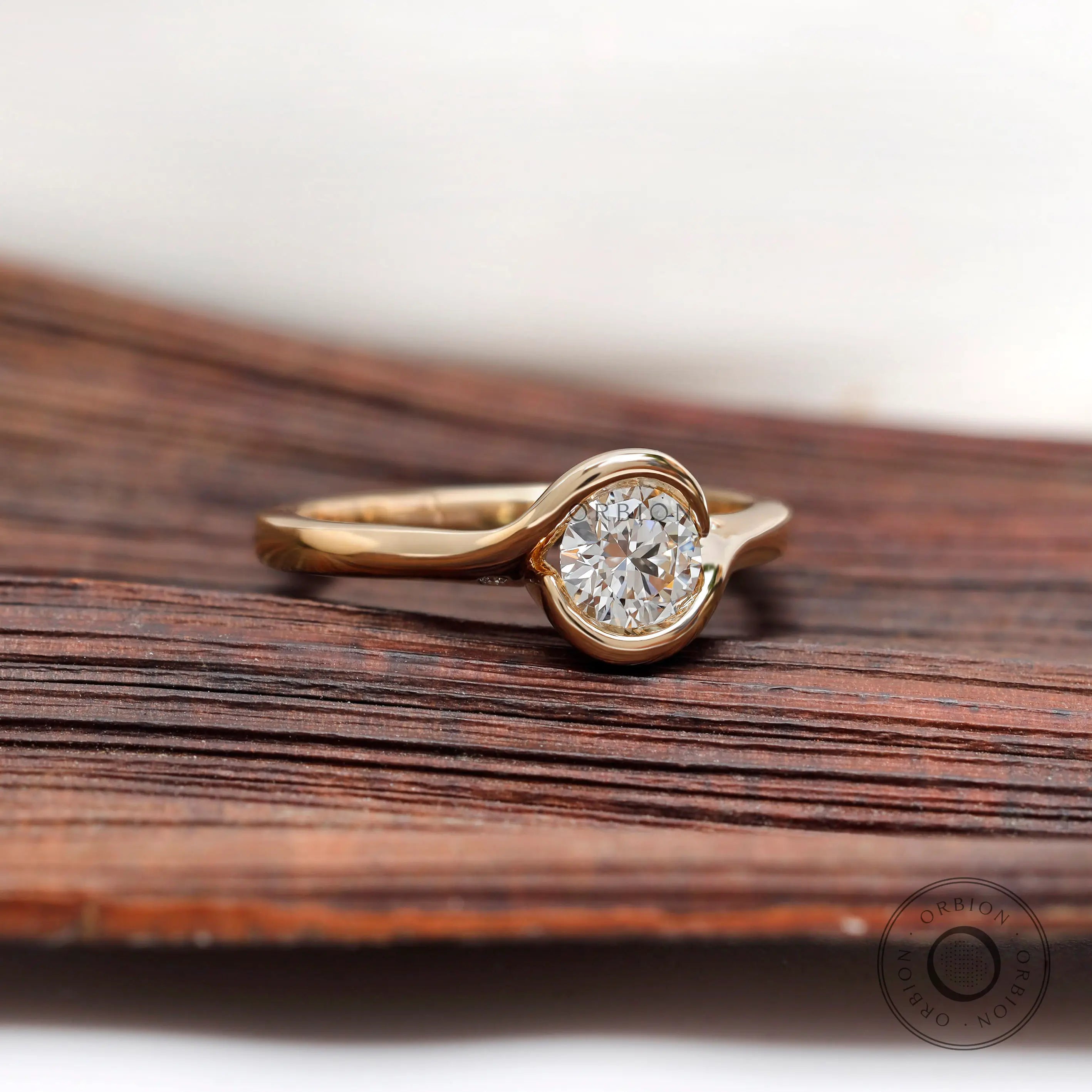 Minimal round diamond solitaire ring on wooden surface