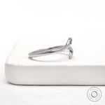 White gold open wrap snake ring featuring a flush set blue diamond