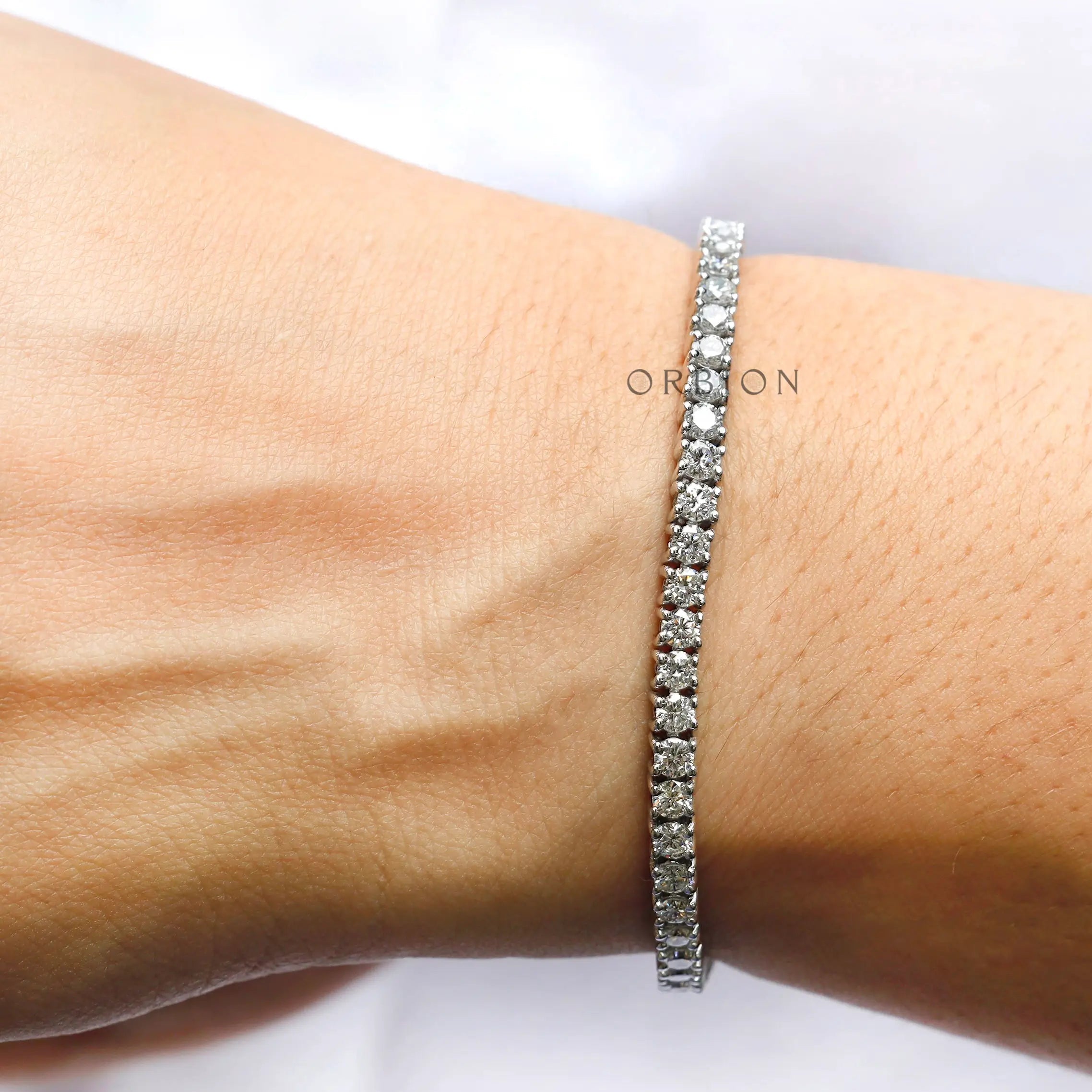 Round brilliant lab diamond tennis bracelet on wrist close-up