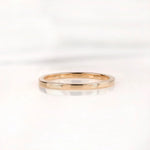 Slim polished gold wedding band shown from front on white background