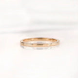 Slim polished gold wedding band shown from front on white background