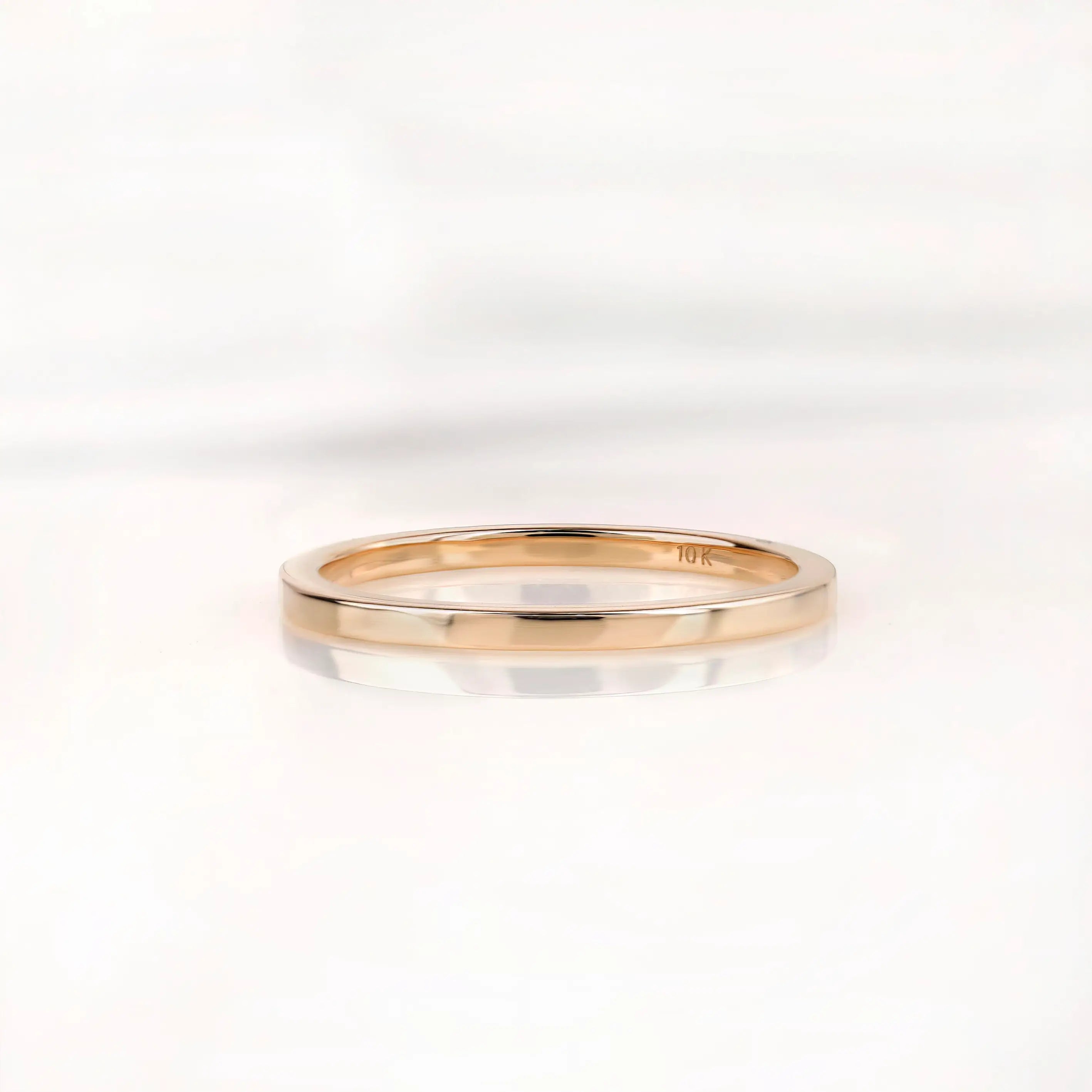 Slim polished gold wedding band shown from front on white background